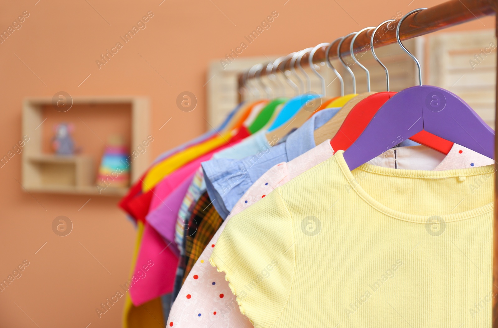 Photo of Different child's clothes hanging on rack indoors, closeup