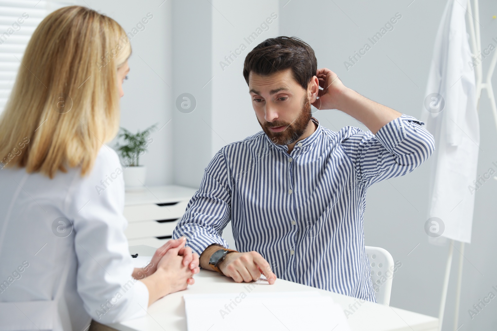 Photo of Doctor consulting patient at white table in clinic