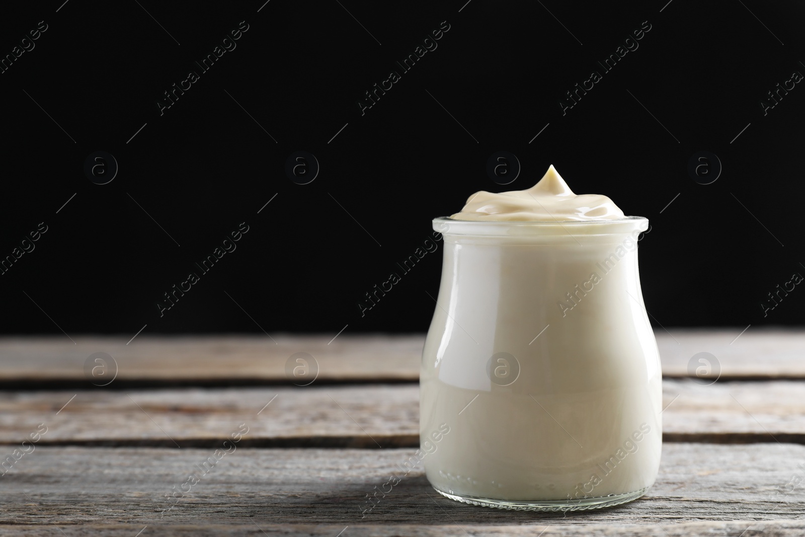 Photo of Fresh mayonnaise sauce in glass jar on wooden table, space for text