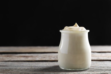 Photo of Fresh mayonnaise sauce in glass jar on wooden table, space for text