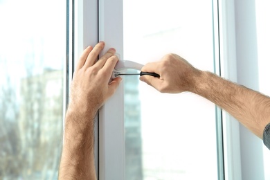 Photo of Professional construction worker installing window indoors, closeup