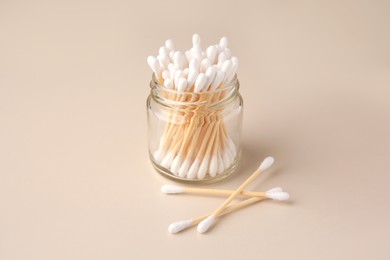 Jar and clean cotton buds on beige background