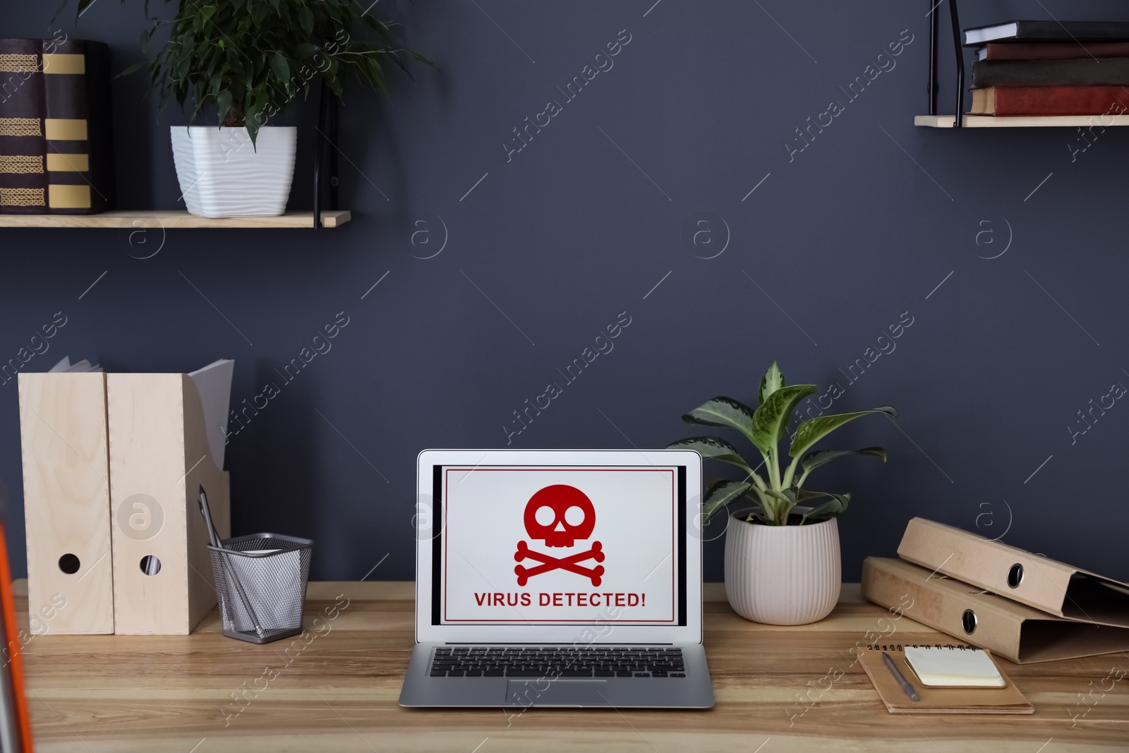 Photo of Laptop with warning about virus attack on wooden table in office