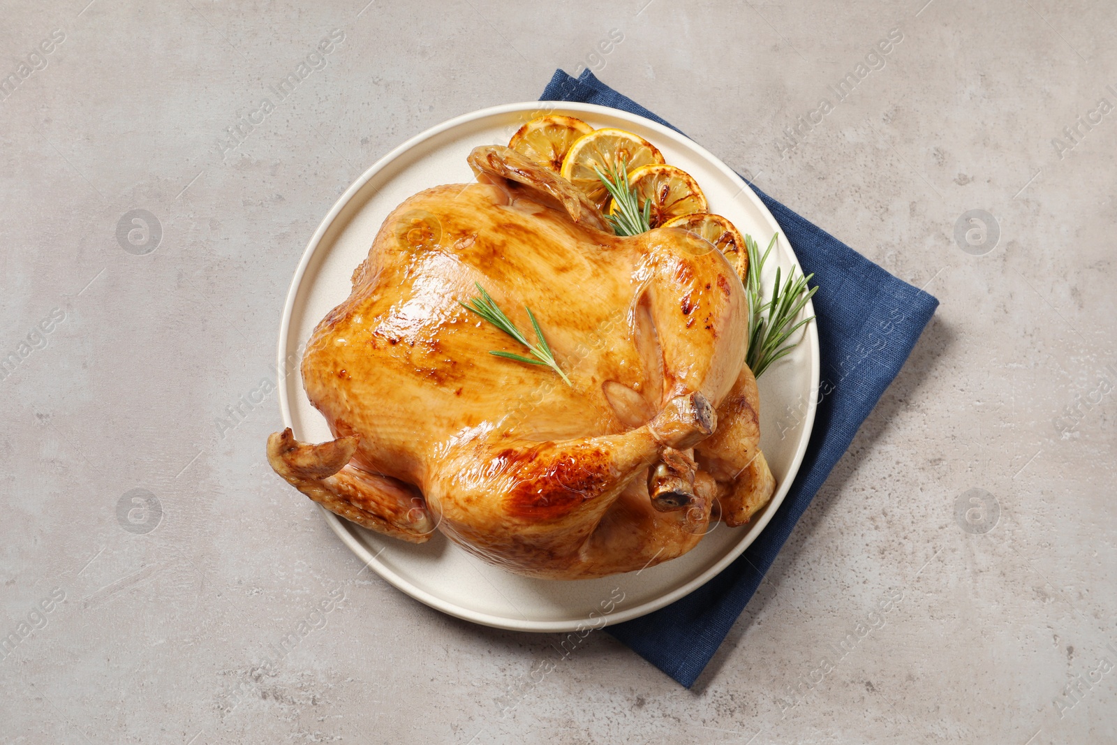 Photo of Tasty roasted chicken with rosemary and lemon on light grey table, top view