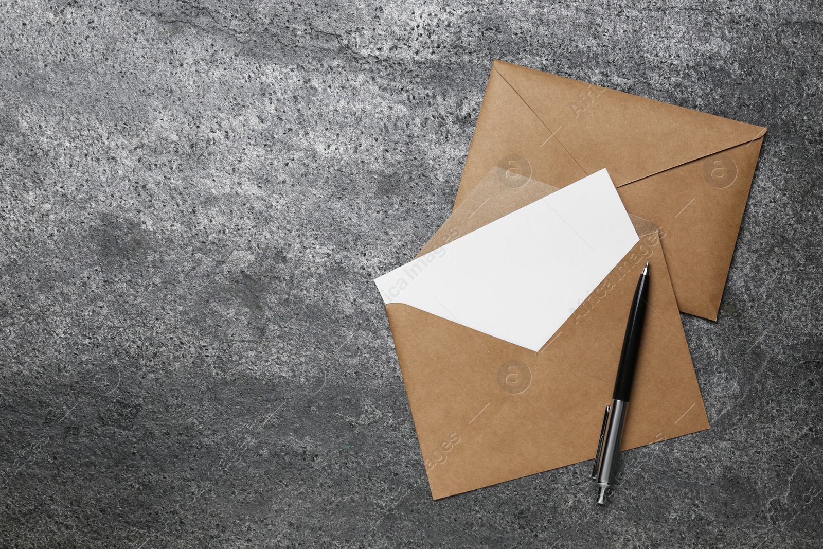 Photo of Envelopes with blank paper card and pen on grey table, flat lay. Space for text