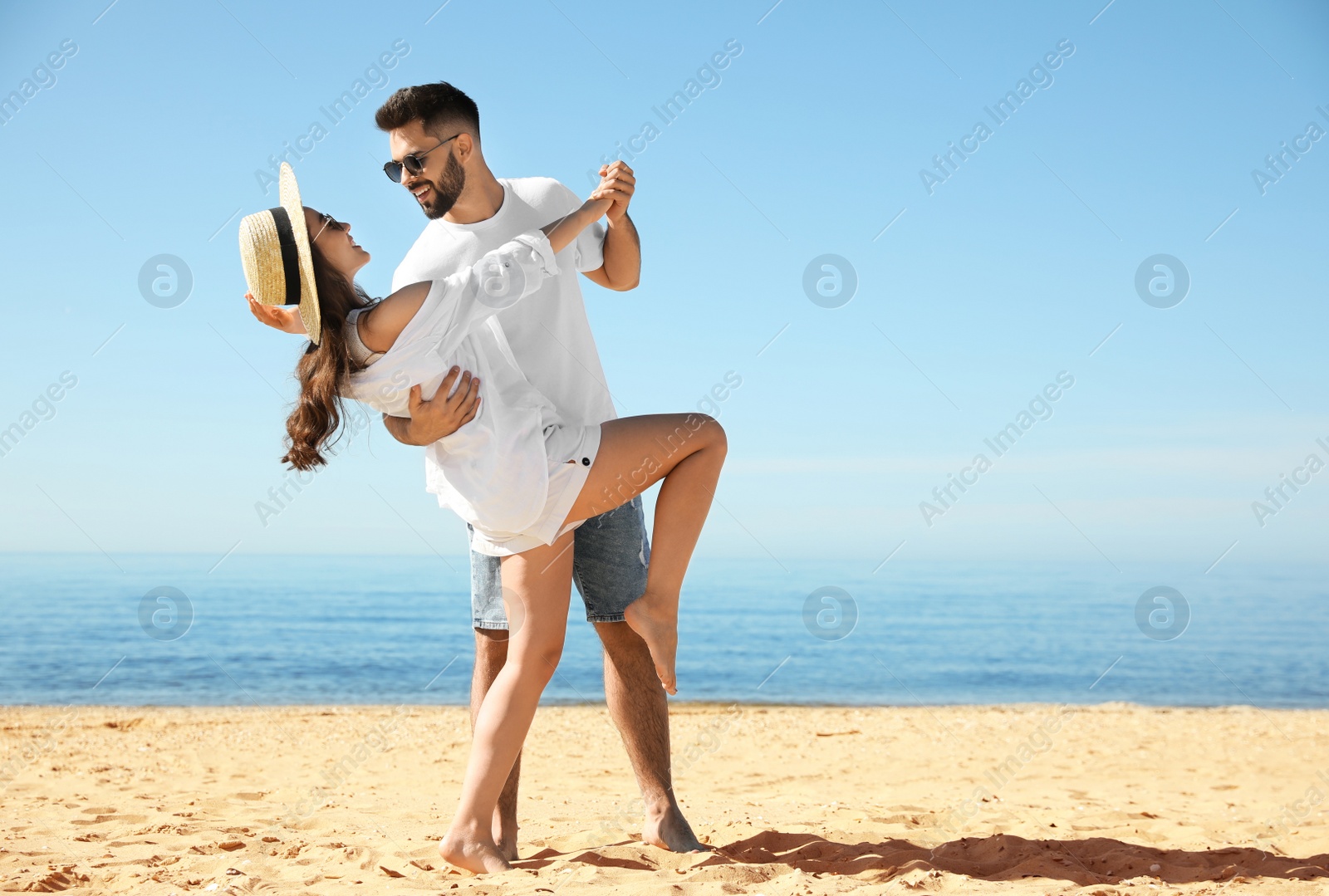 Photo of Happy young couple dancing on beach near sea. Honeymoon trip