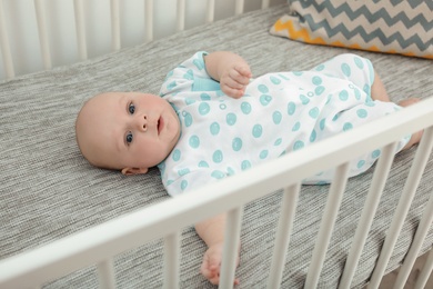 Photo of Cute little baby lying in comfortable crib