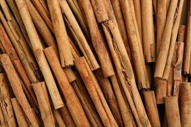 Photo of Aromatic cinnamon sticks as background, top view