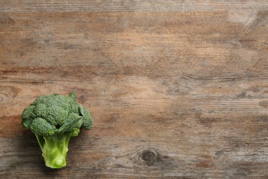 Photo of Fresh raw broccoli on wooden table, top view with space for text