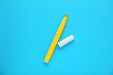 Photo of Bright yellow marker and cap on light blue background, flat lay