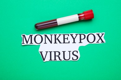 Photo of Words Monkeypox Virus and test tube with blood sample on green background, flat lay