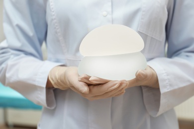 Photo of Doctor holding silicone implants for breast augmentation in clinic, closeup. Cosmetic surgery