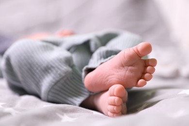 Photo of Cute newborn baby lying on bed, closeup of legs