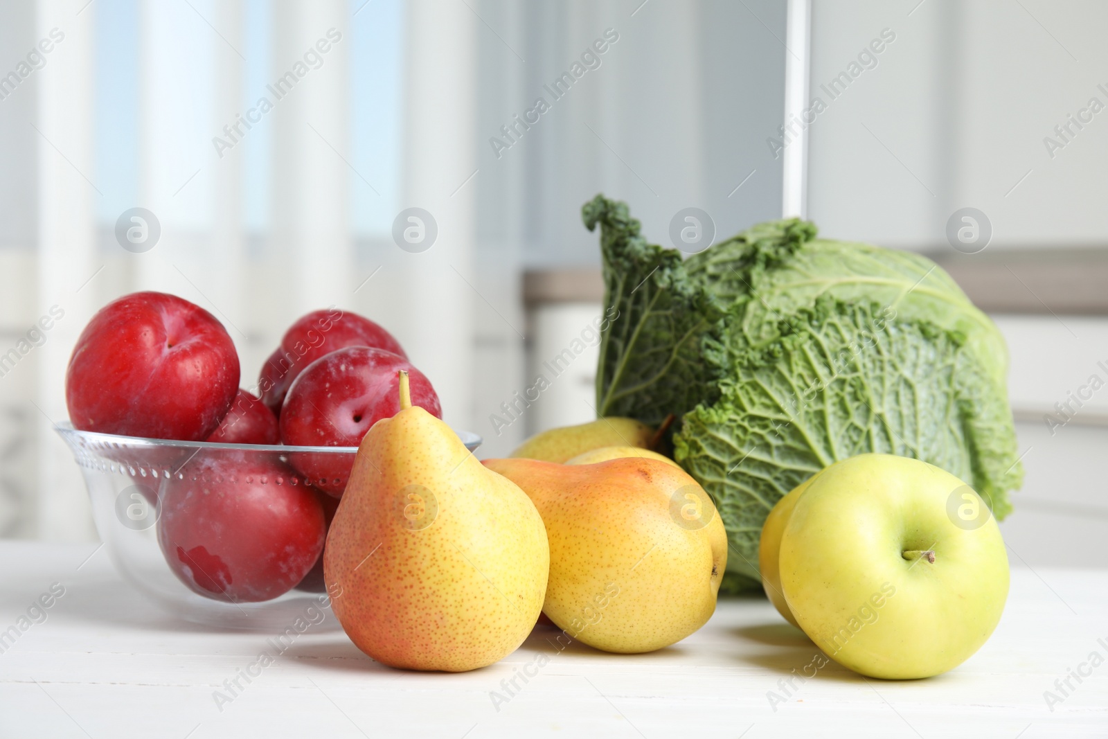 Photo of Fresh fruits and savoy cabbage on white wooden table indoors. Food poisoning concept