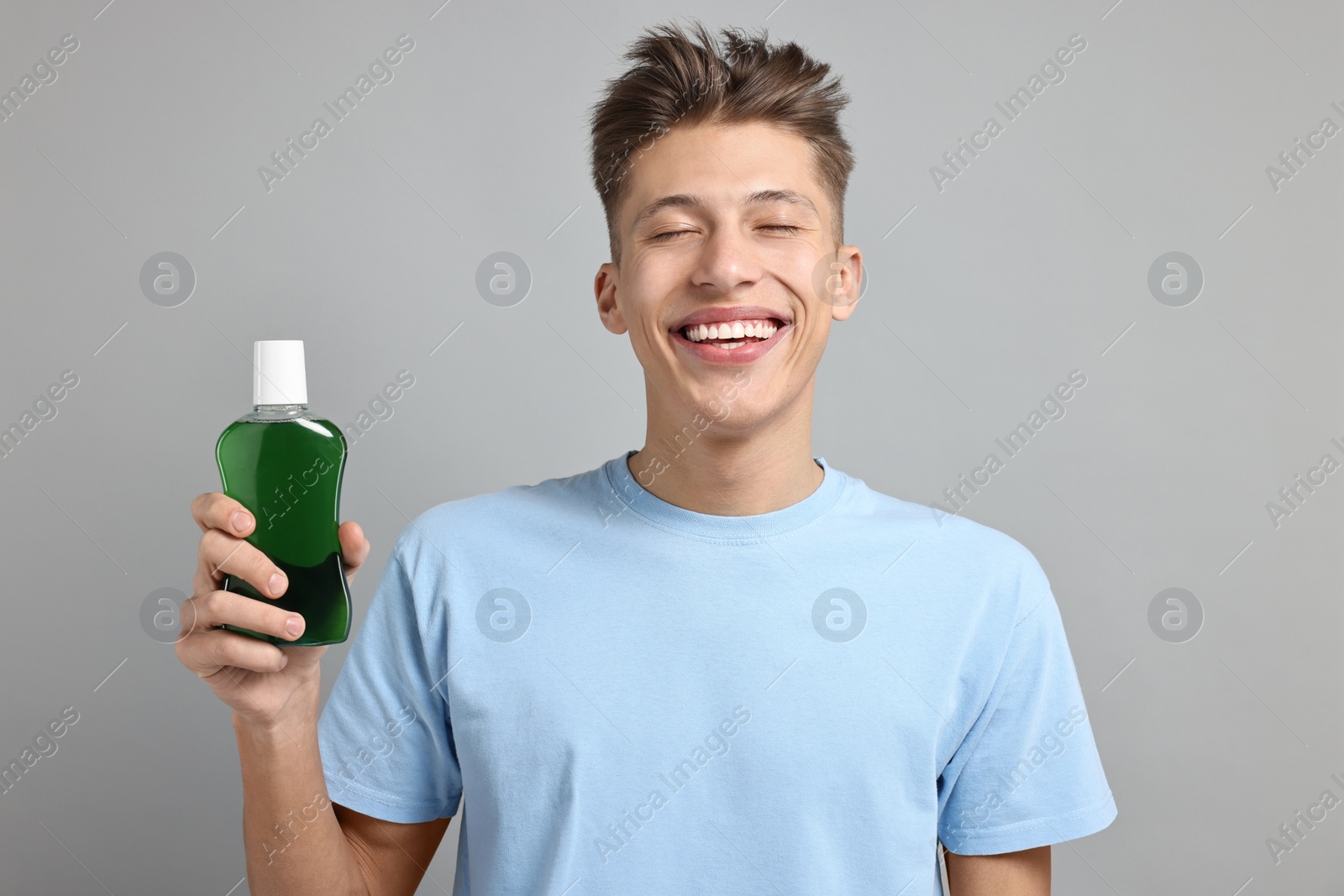 Photo of Young man with mouthwash on light grey background