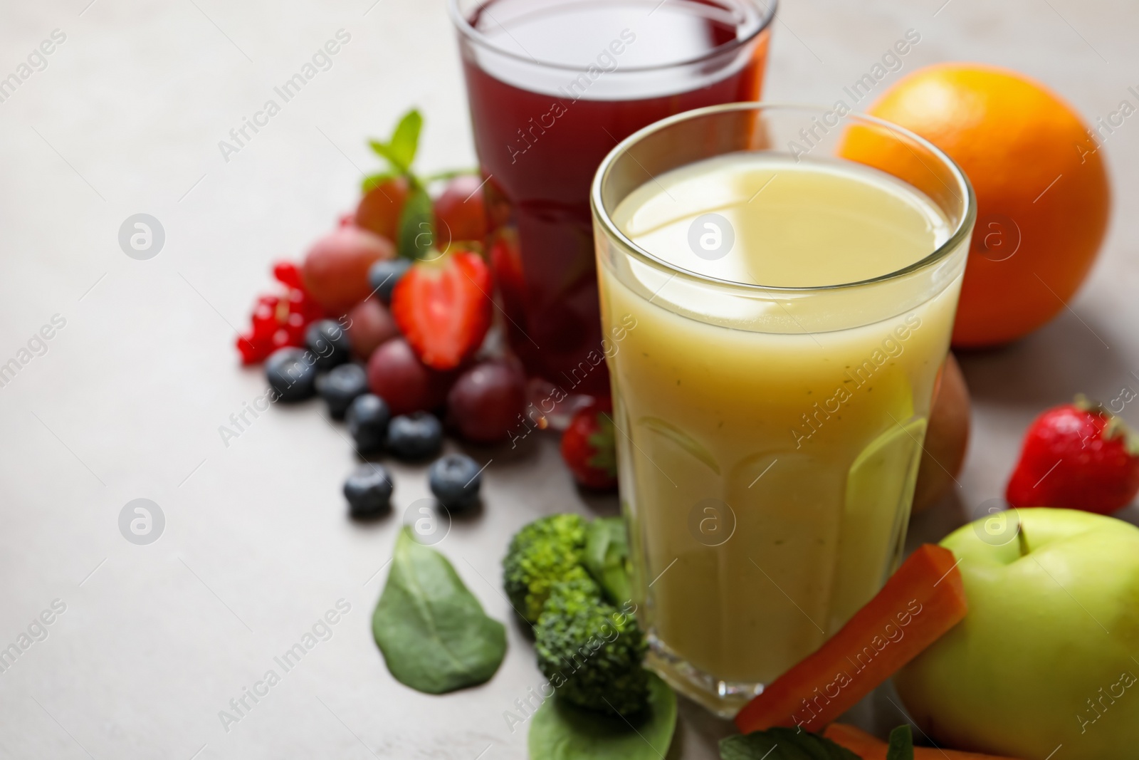 Photo of Delicious juice and fresh ingredients on grey table, closeup. Space for text