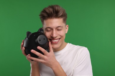 Photo of Happy man with piggy bank on green background