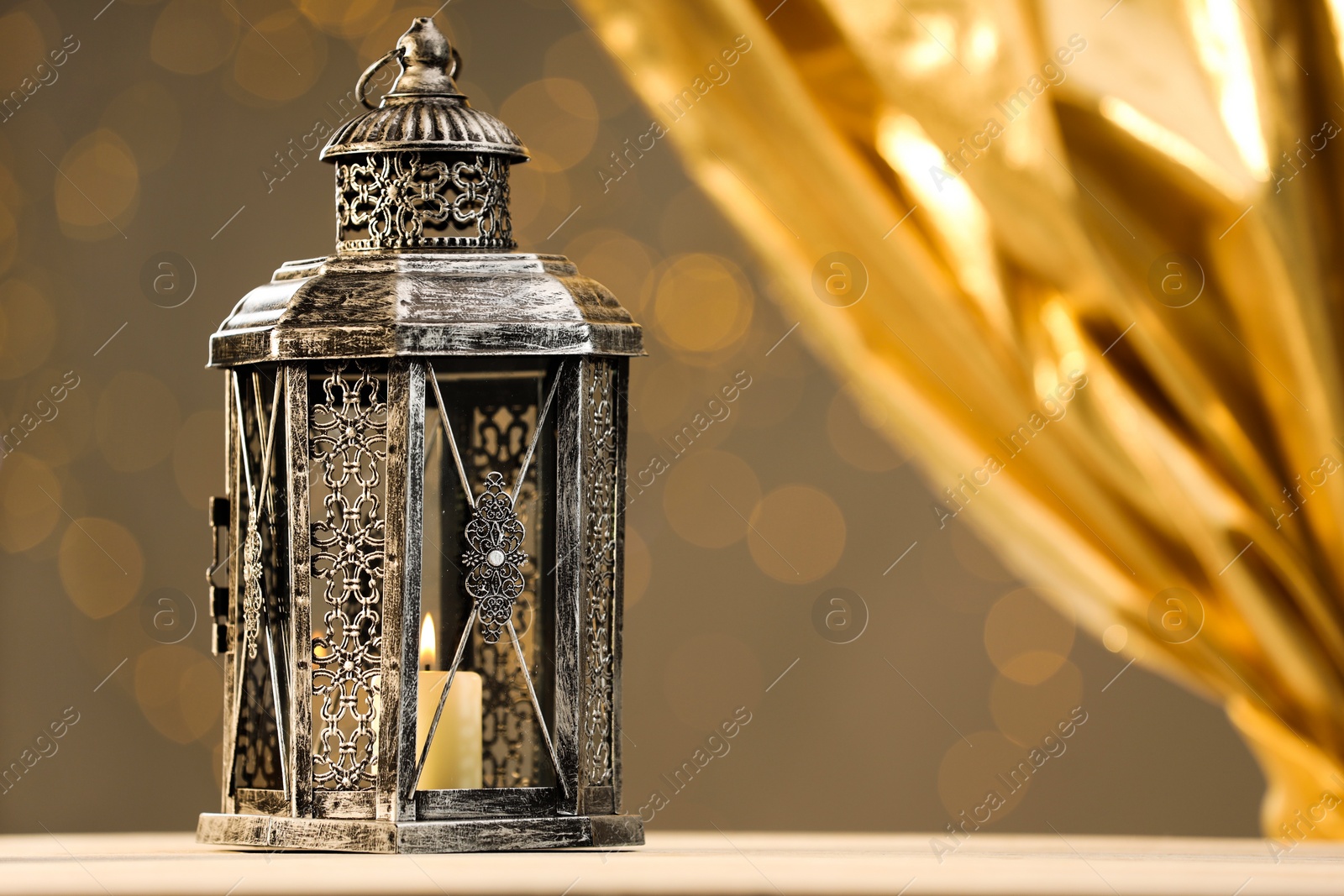 Photo of Arabic lantern on table against blurred lights, space for text