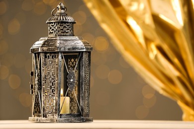 Arabic lantern on table against blurred lights, space for text