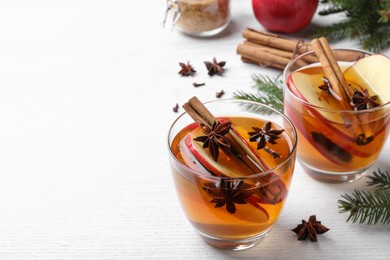 Hot mulled cider and fir branches on white wooden table, space for text