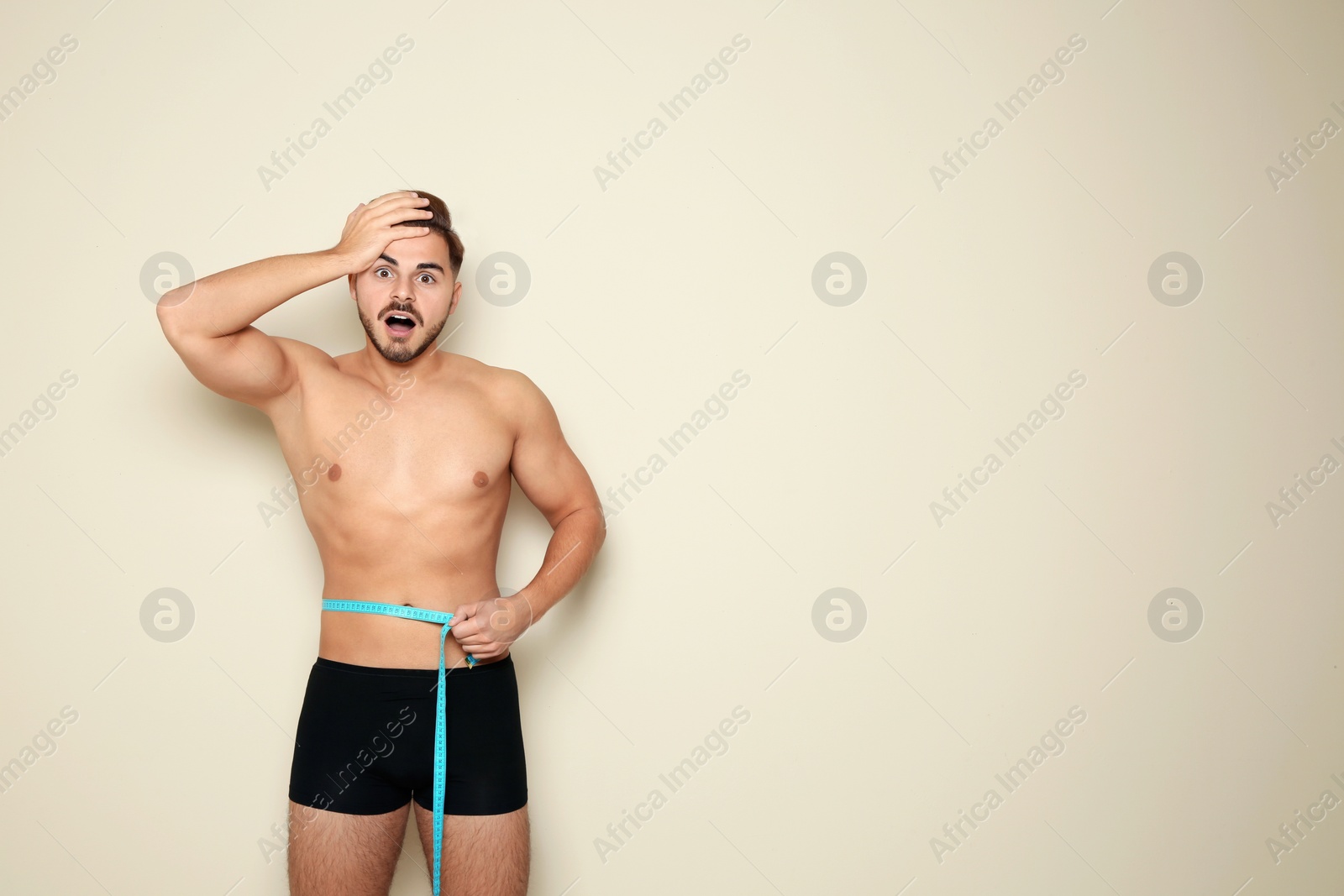 Photo of Fit man measuring his waist on color background, space for text. Weight loss