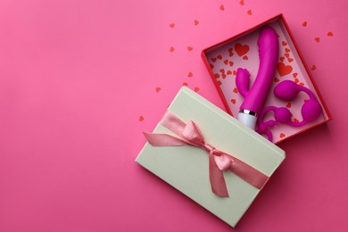Photo of Gift box with sex toys on pink background, top view. Space for text