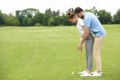 Photo of Coach teaching woman to play golf on green course