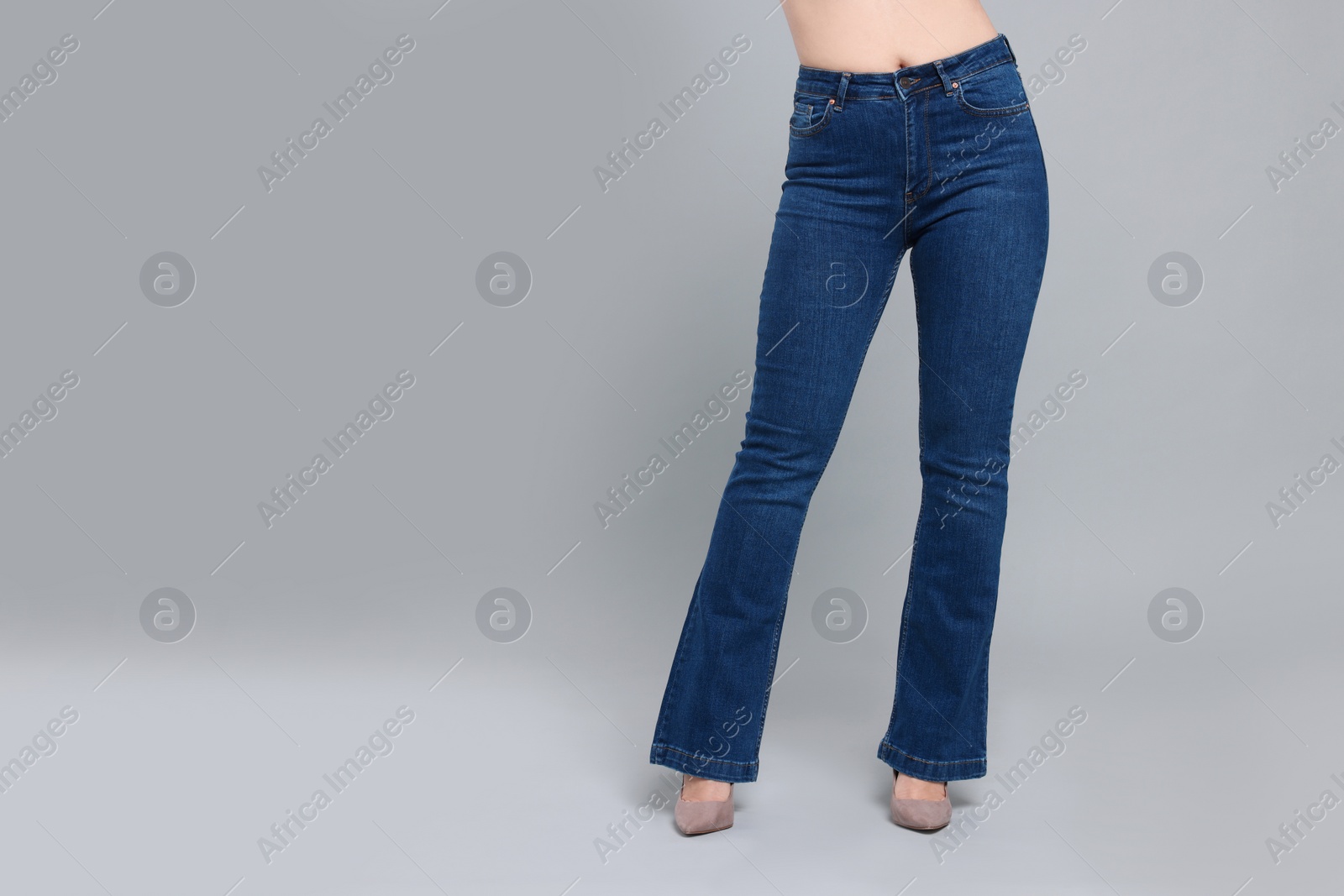 Photo of Woman in stylish jeans on grey background, closeup. Space for text