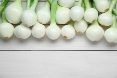 Photo of Whole green spring onions on white wooden table, flat lay. Space for text