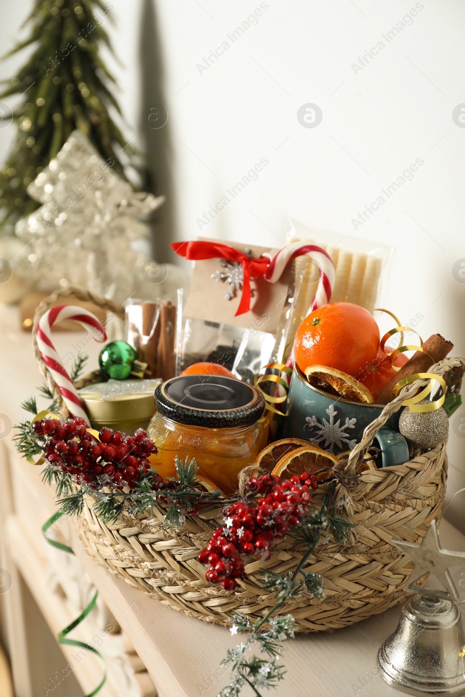 Photo of Wicker basket with gift set and Christmas decor on shelf