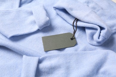 Photo of Blank grey tag on light blue sweater. Space for text