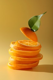 Photo of Slices of juicy orange and leaf on beige background