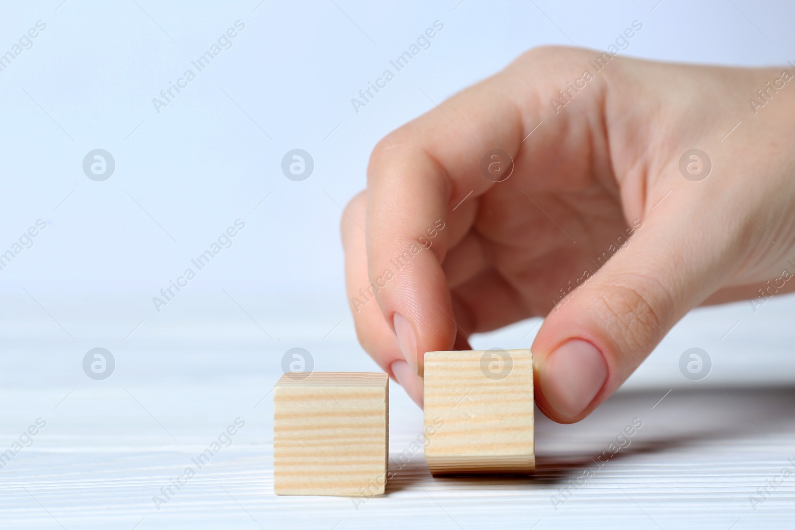 Photo of Woman arranging cubes on white background, closeup with space for text. Idea concept