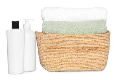 Photo of Wicker basket with soft terry towels and cosmetic products on white background