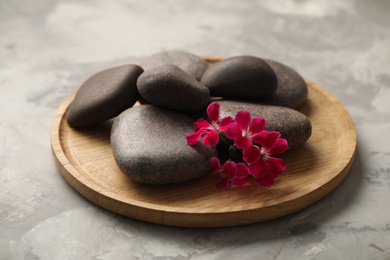 Photo of Spa stones and red flowers on grey table, closeup