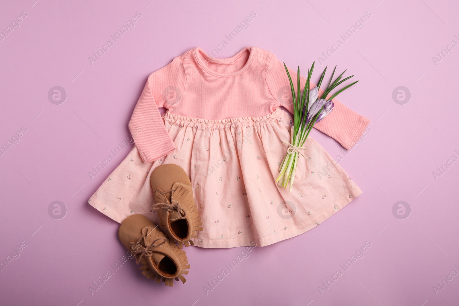 Photo of Flat lay composition with child's clothes, booties and flowers on pink background