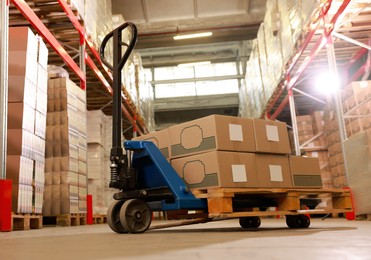 Image of Manual forklift with cardboard boxes in warehouse. Logistics concept