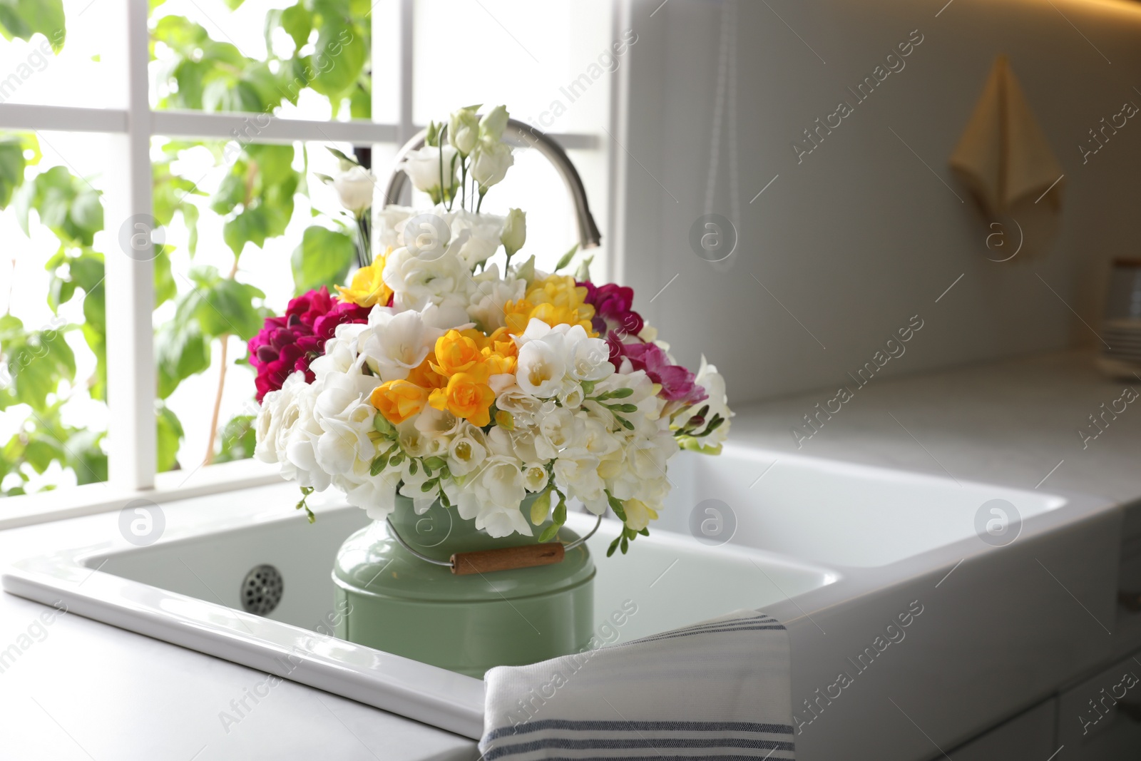 Photo of Beautiful bouquet with fresh freesia flowers in kitchen sink