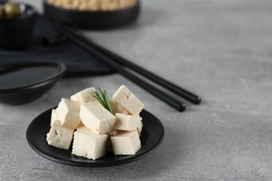 Pieces of delicious tofu with rosemary on grey table. Space for text