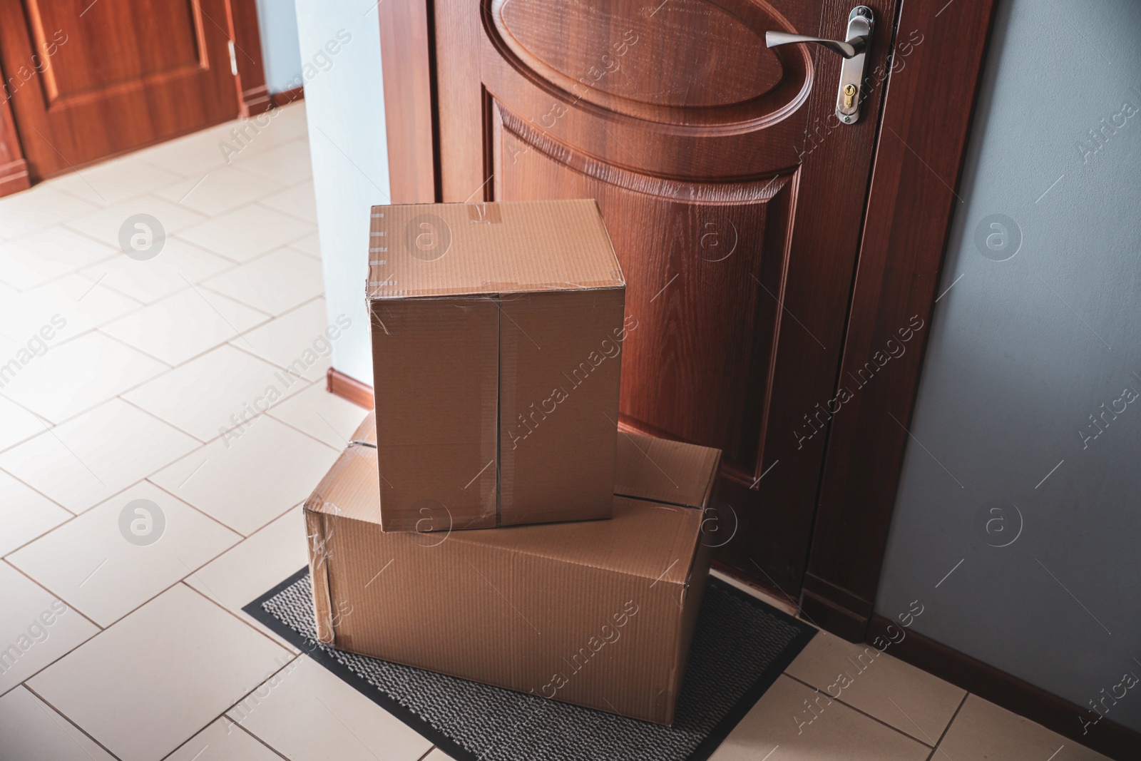 Photo of Cardboard boxes on rug near door. Parcel delivery service