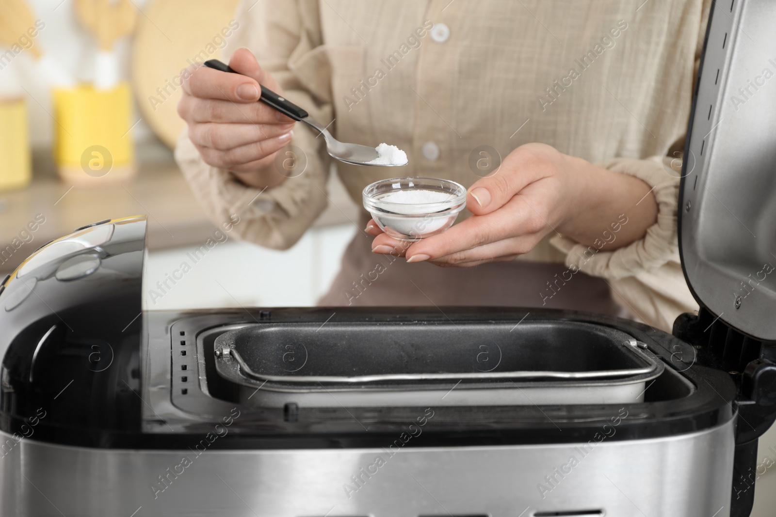 Photo of Making dough. Woman adding salt into breadmaker machine, closeup