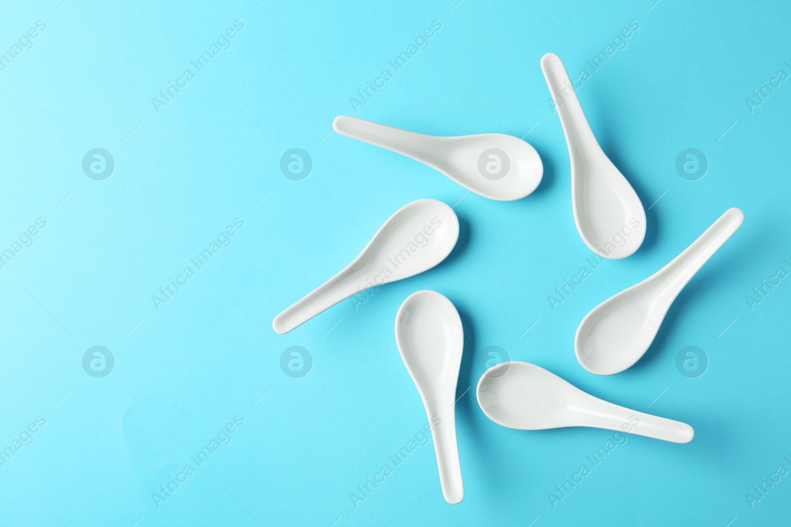 Photo of Miso soup spoons on blue background, flat lay. Space for text