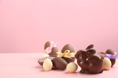 Photo of Chocolate Easter bunny and eggs on pink wooden table. Space for text