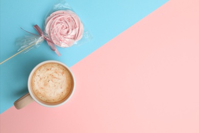 Cup of coffee and candy on color background, top view. Space for text