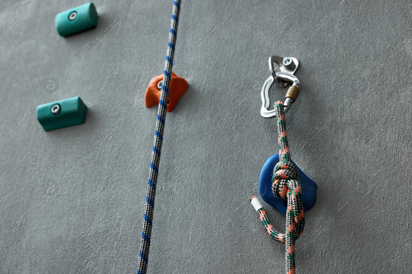 Photo of Colorful climbing wall with holds and ropes. Extreme sport