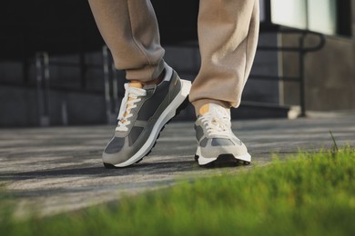 Man wearing pair of stylish sneakers outdoors, closeup