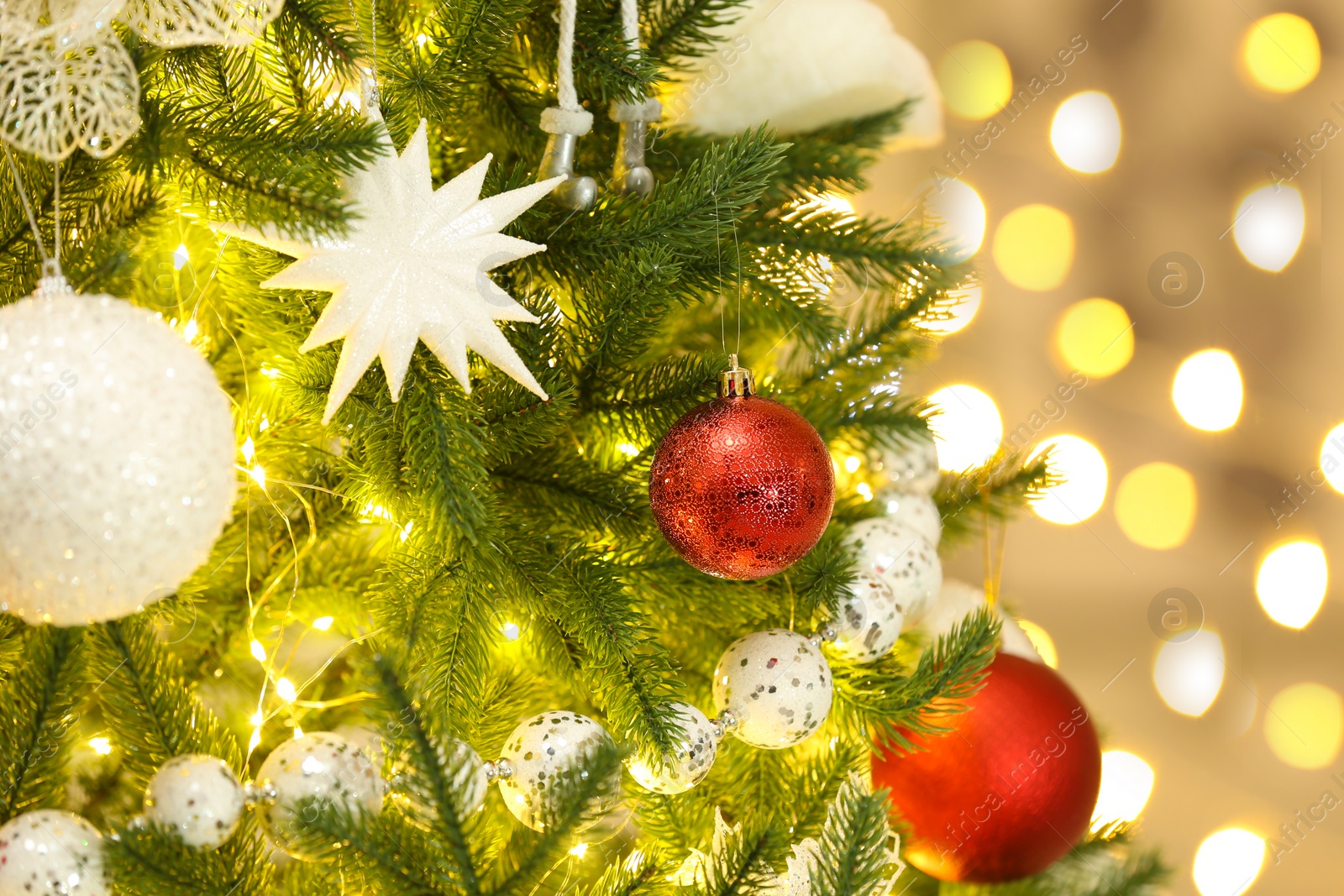 Photo of Color holiday baubles hanging on Christmas tree against blurred lights, closeup