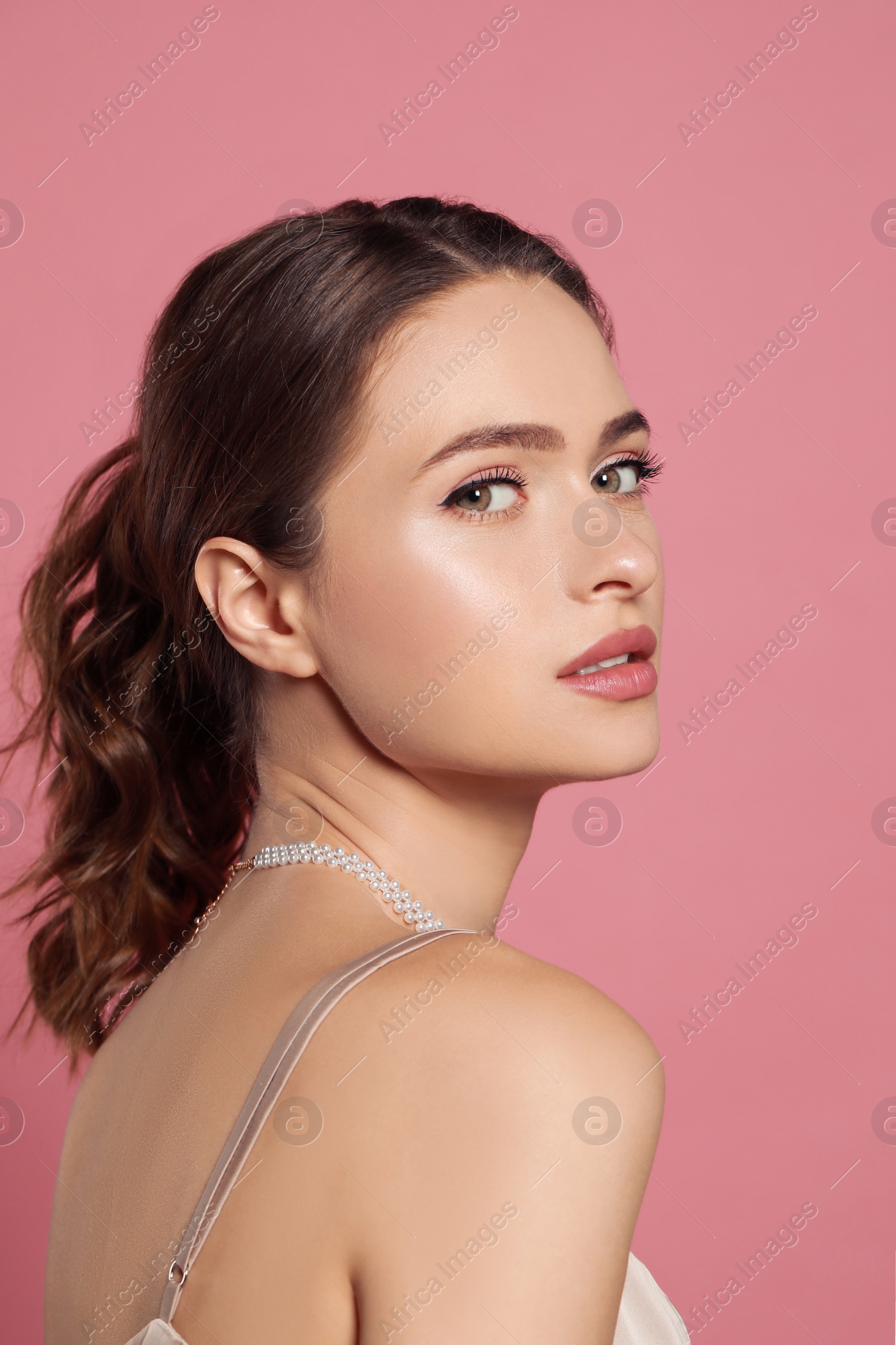 Photo of Young woman wearing elegant pearl necklace on pink background