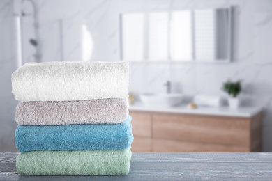 Image of Stack of fresh towels on grey wooden table in bathroom. Space for text