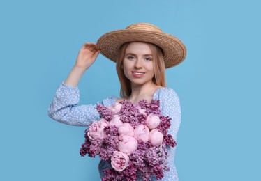 Beautiful woman with bouquet of spring flowers on light blue background